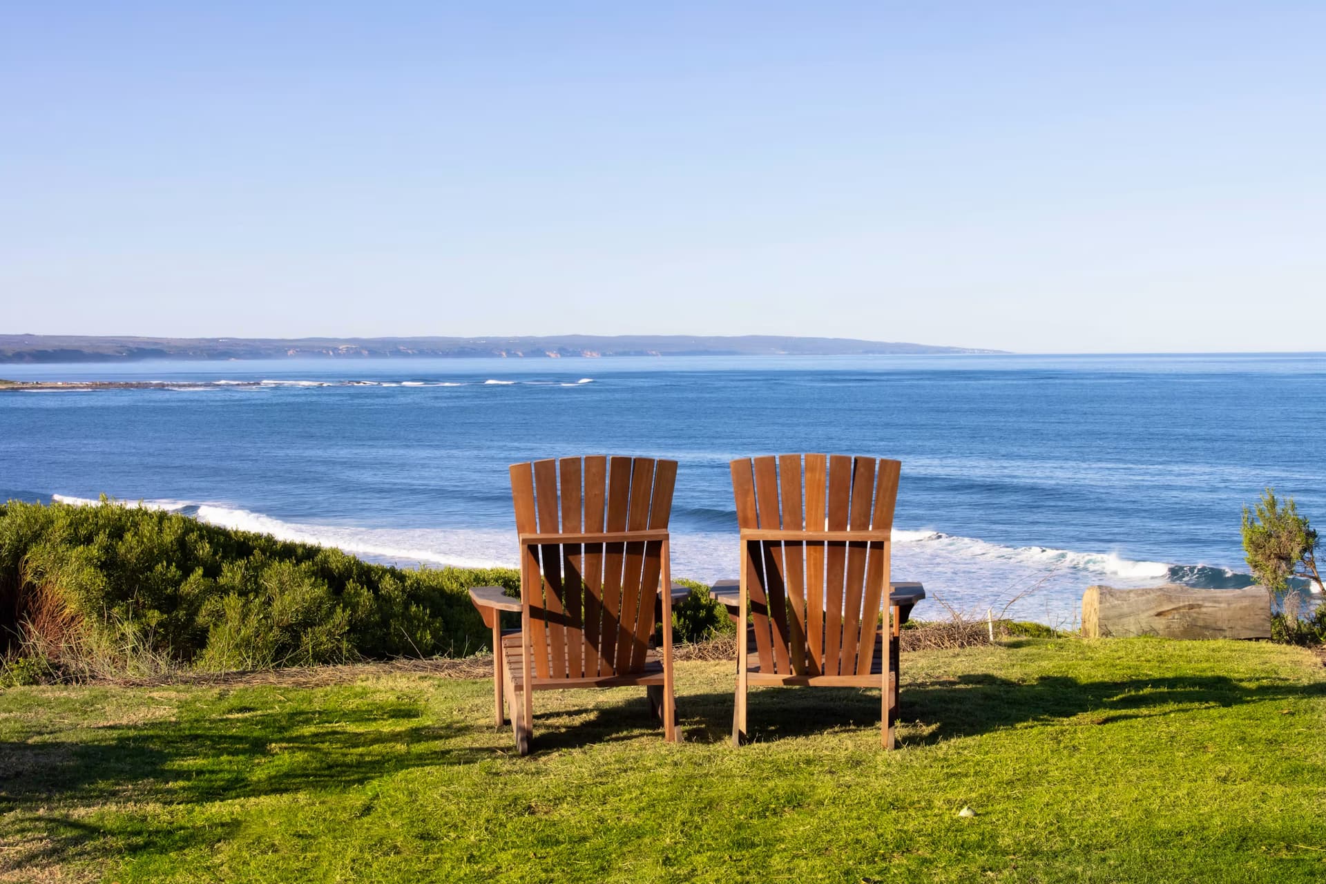 Two chairs facing the ocean from Casa Caro's lawn