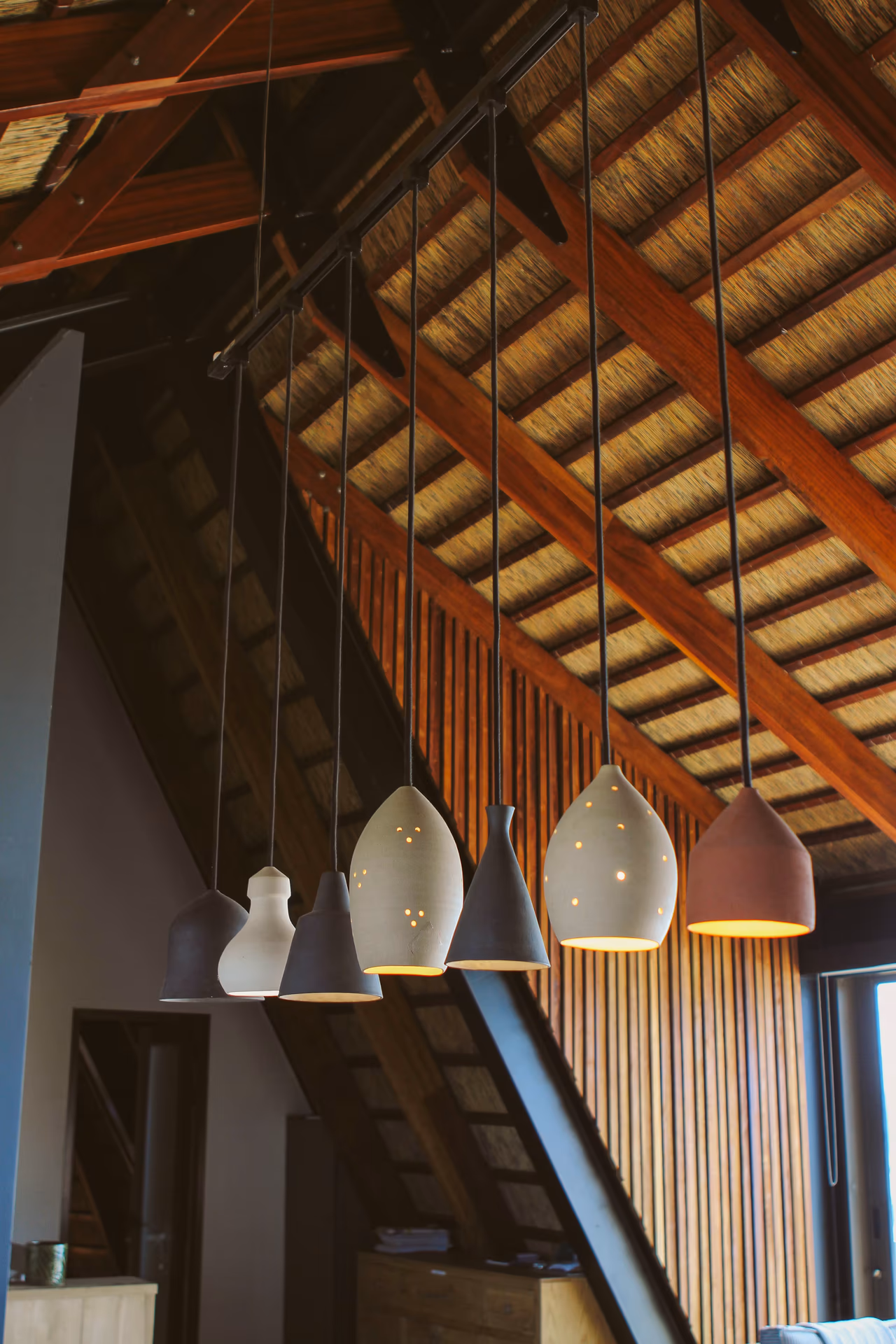 Pendant lights suspended beneath Casa Caro's exposed thatch roof